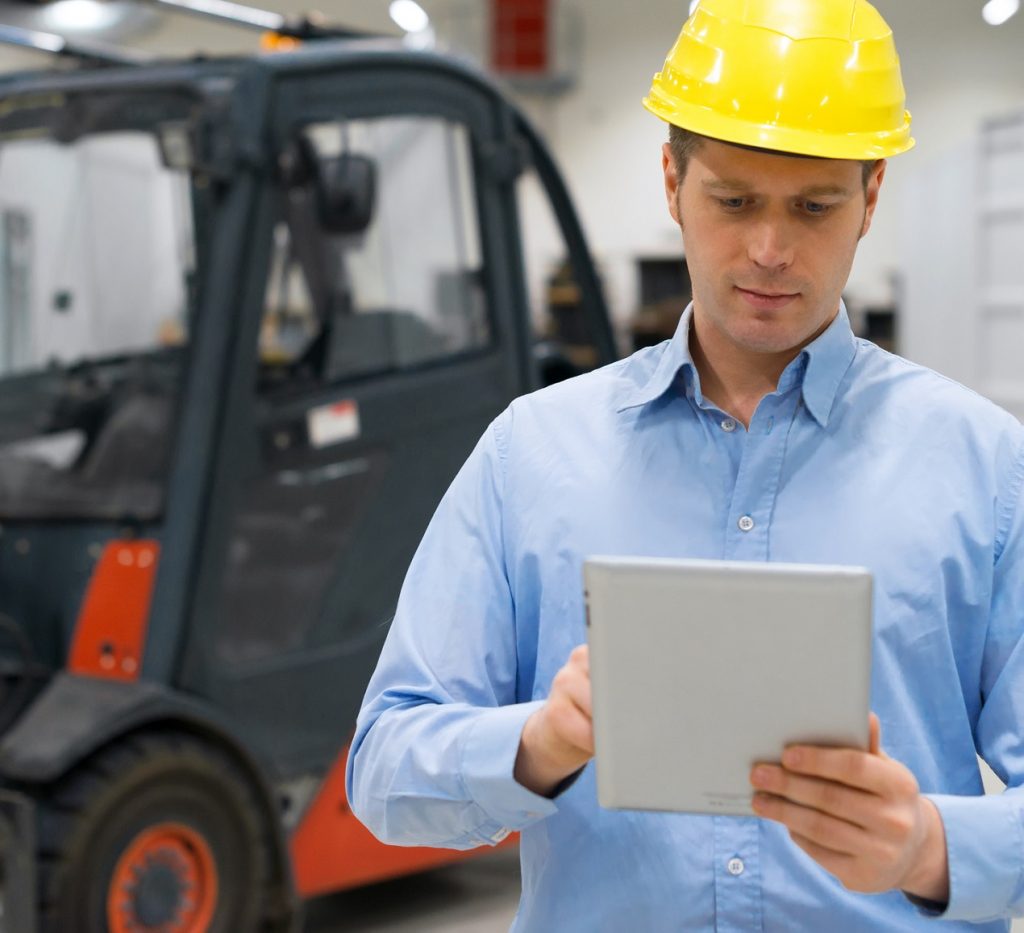 Warehouseman in hard hat with tablet pc at warehouse.
